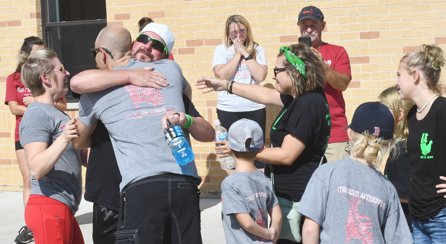Donor family meets recipient’s family at ‘Celebrate Life’ event. Their families — linked forever by a bond few could image — met for the first time Sunday during a “Surprise 5K” walk and run in Owensville to benefit the Mid-America Transplant program’s Celebrate Life campaign. Chris McDougald, Lebanon, Mo., (facing camera) embraces Brett Palmer of Owensville as their respective wives, Danielle Palmer (left) and Stephanie McDougald reach out to greet each other with a hug. The McDougald’s son, Ki, 3, died Oct. 29, 2019, from injuries in a “freak” all-terrain vehicle crash three days earlier. The Palmer’s son, Truett, born with a genetic heart condition, received Ki’s heart the following day. Truett would live another year before what was described by his mother as a common “bug” caused his death on Nov. 3, 2020. The Palmers had been at their’s son’s one-year transplant checkup when he fell ill. Truett’s transplanted heart from the McDougald’s son was healthy. A “common ailment” causing a lung infection was cited as his cause of death at the age of 3 years and 8 months. As friends and family of the Truetts waited to begin the 5K fund-raiser, the families of two boys — forever linked together through organ donation — embraced. Then walked together.